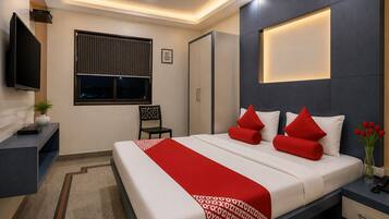 Una habitación de hotel moderna con una cama, mesita de noche, televisor y ventana con persianas.