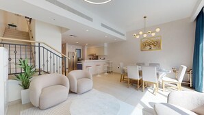 Una sala de estar moderna con una escalera, un comedor y una cocina al fondo.