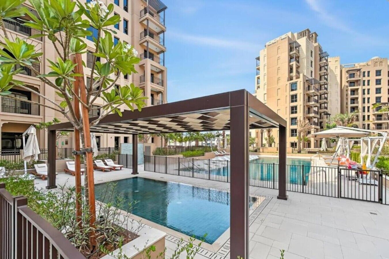 A residential building with a swimming pool, outdoor seating, and a pergola.