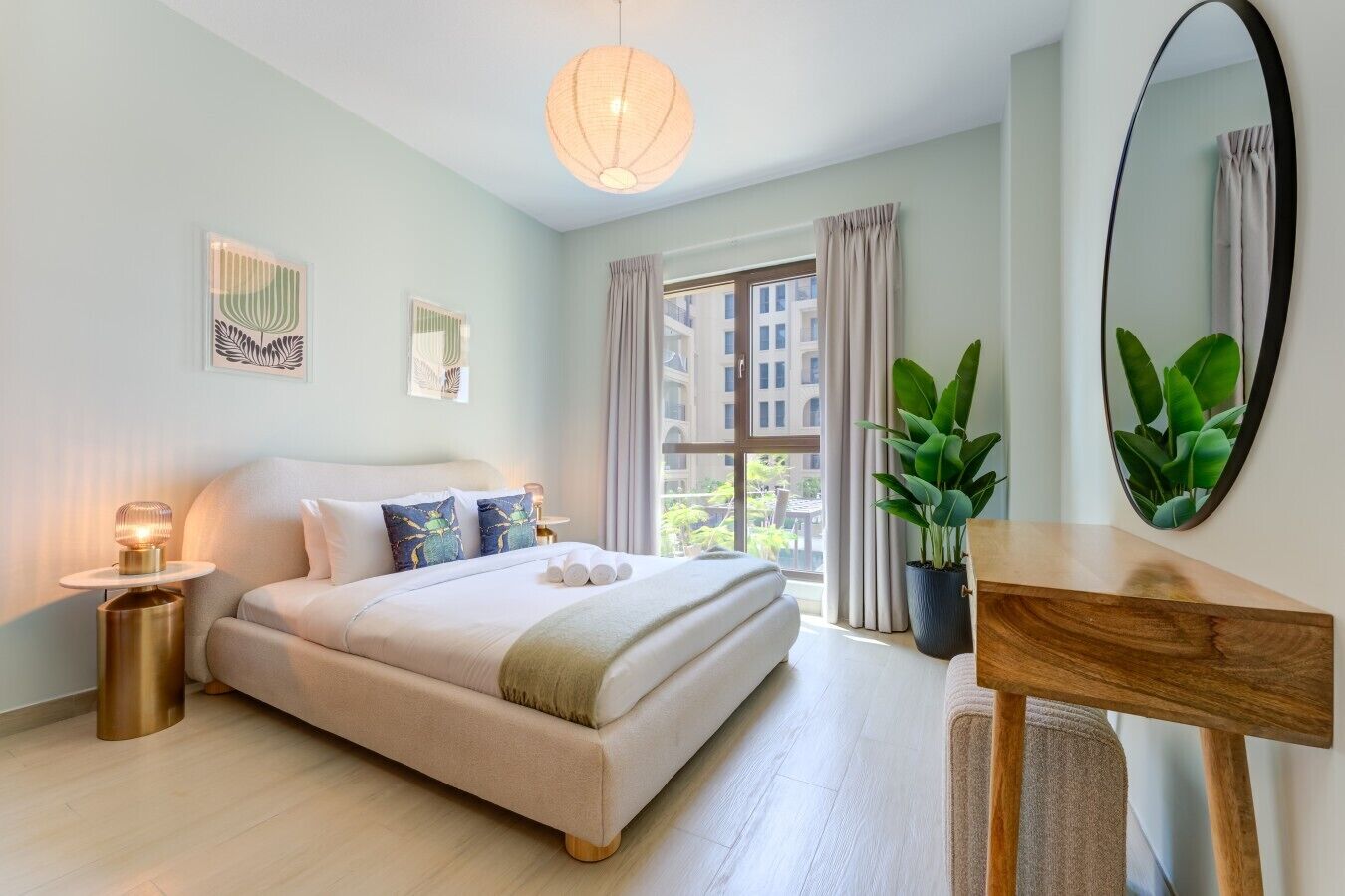 Une chambre à coucher moderne avec un lit, une table de chevet, une lampe, une plante en pot et un grand miroir.