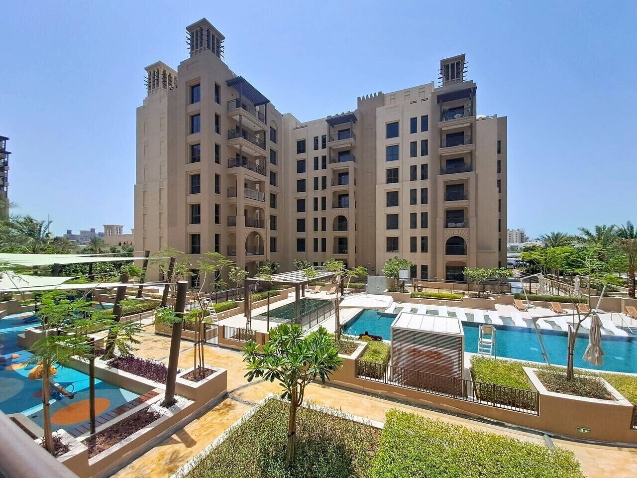 Un hôtel doté de plusieurs piscines, d’espaces extérieurs aménagés et d’un grand bâtiment avec des balcons.