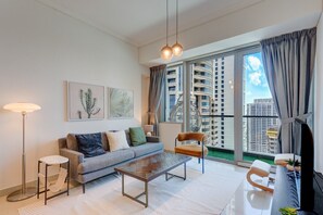 A modern living room with a sofa, coffee table, and a chair. There is a large window with curtains, a floor lamp, and artwork on the wall. - Elevated 1 Bed on 34th Floor l City View l Marina (Dubai Marina)