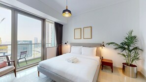 Ein Hotelzimmer mit einem großen Bett, einem Nachttisch, einer Zimmerpflanze und Blick auf die Stadt vom Balkon.