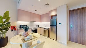 A modern kitchen with stainless steel appliances, a dining area with a round table, and a potted plant. - Contemporary 1 Bed Near Burj Al Arab l Wild Wadi (Madinat Jumeirah Living)