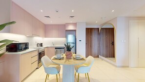 A modern kitchen with a dining area, featuring a microwave, stove, sink, and a round table with chairs. - Contemporary 1 Bed Near Burj Al Arab l Wild Wadi (Madinat Jumeirah Living)