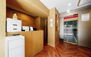 Uma área de recepção com balcão de madeira, um armário de arquivo branco e um aviso fixado na parede.