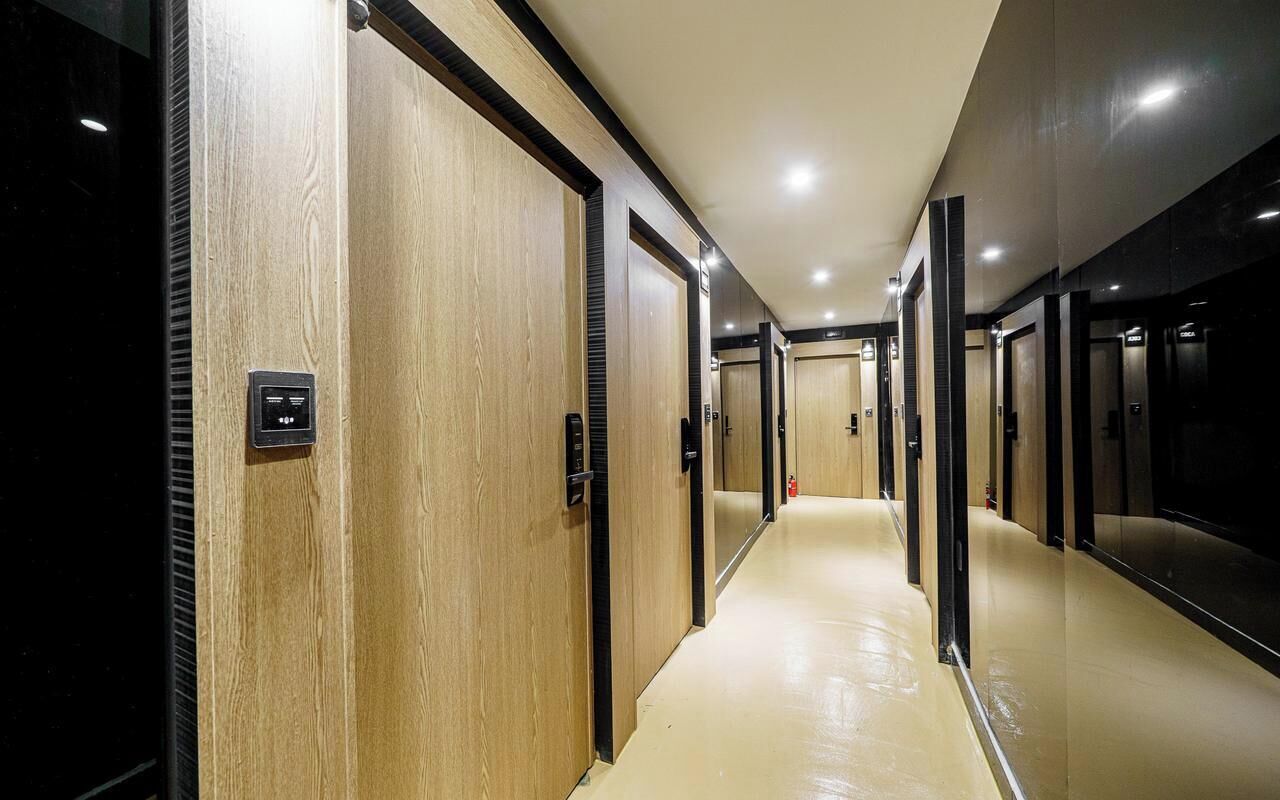 Un pasillo con puertas de madera y piso claro, que conduce a los ascensores.