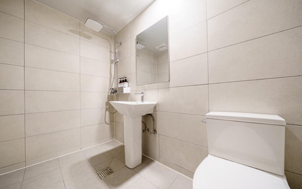 Un baño con inodoro, lavamanos, ducha y espejo.