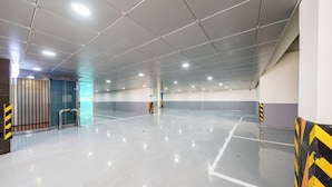 Un amplio estacionamiento interior con piso de baldosas limpias y un techo alto con iluminación empotrada.