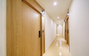 A corridor with wooden doors and a shiny floor, leading to a room.