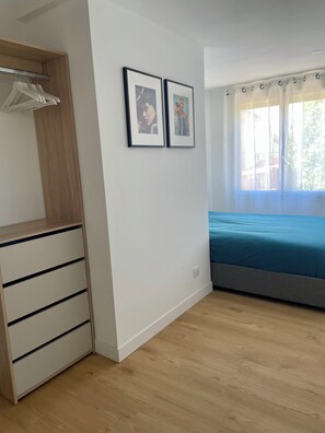 Una stanza con un letto, un armadio in legno e due quadri appesi al muro.