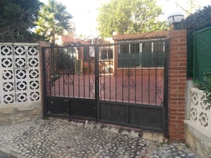 A gated entrance with a patterned metal gate, brick walls, and a cobblestone pathway. - A unique house with a garden, very close to the beach (Playa de San Juan, Cabo Huertas)