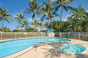 Ein Swimmingpool, umgeben von Palmen und einem weißen Zaun.