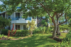 A two-story building with a balcony, surrounded by lush greenery and a well-maintained lawn. - Family Adventure Getaway on the Big Island!
Perfectly located!!! (Cedar Hills)