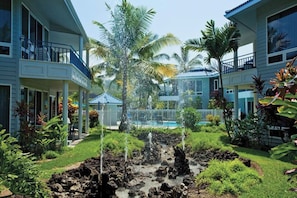 A hotel courtyard with a pool, palm trees, and a waterfall feature. - Family Adventure Getaway on the Big Island!
Perfectly located!!! (Cedar Hills)