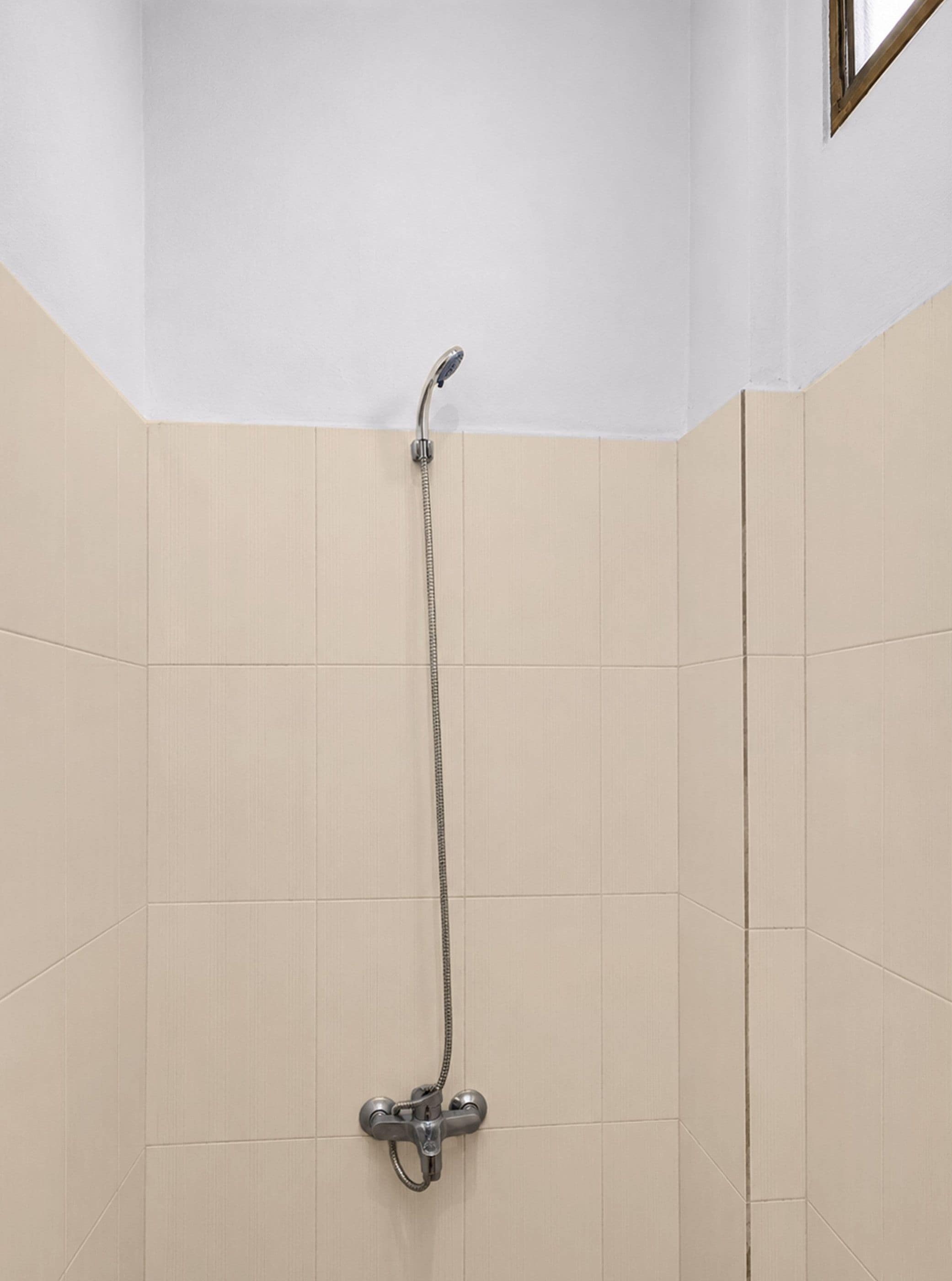 A shower with a handheld showerhead and a wall-mounted faucet.