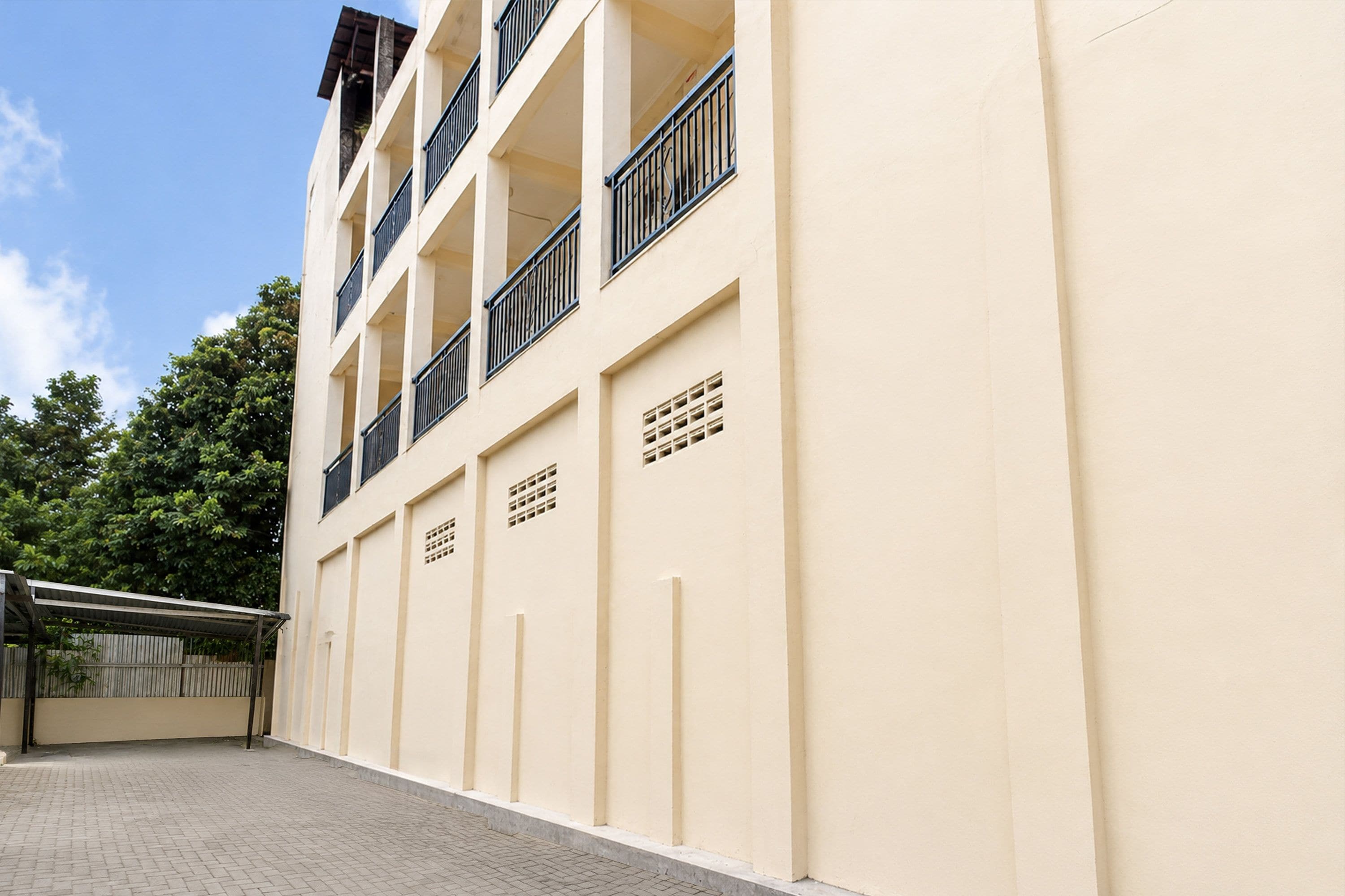 Un immeuble à plusieurs étages doté de balcons, d’une entrée couverte et d’un trottoir dallé.