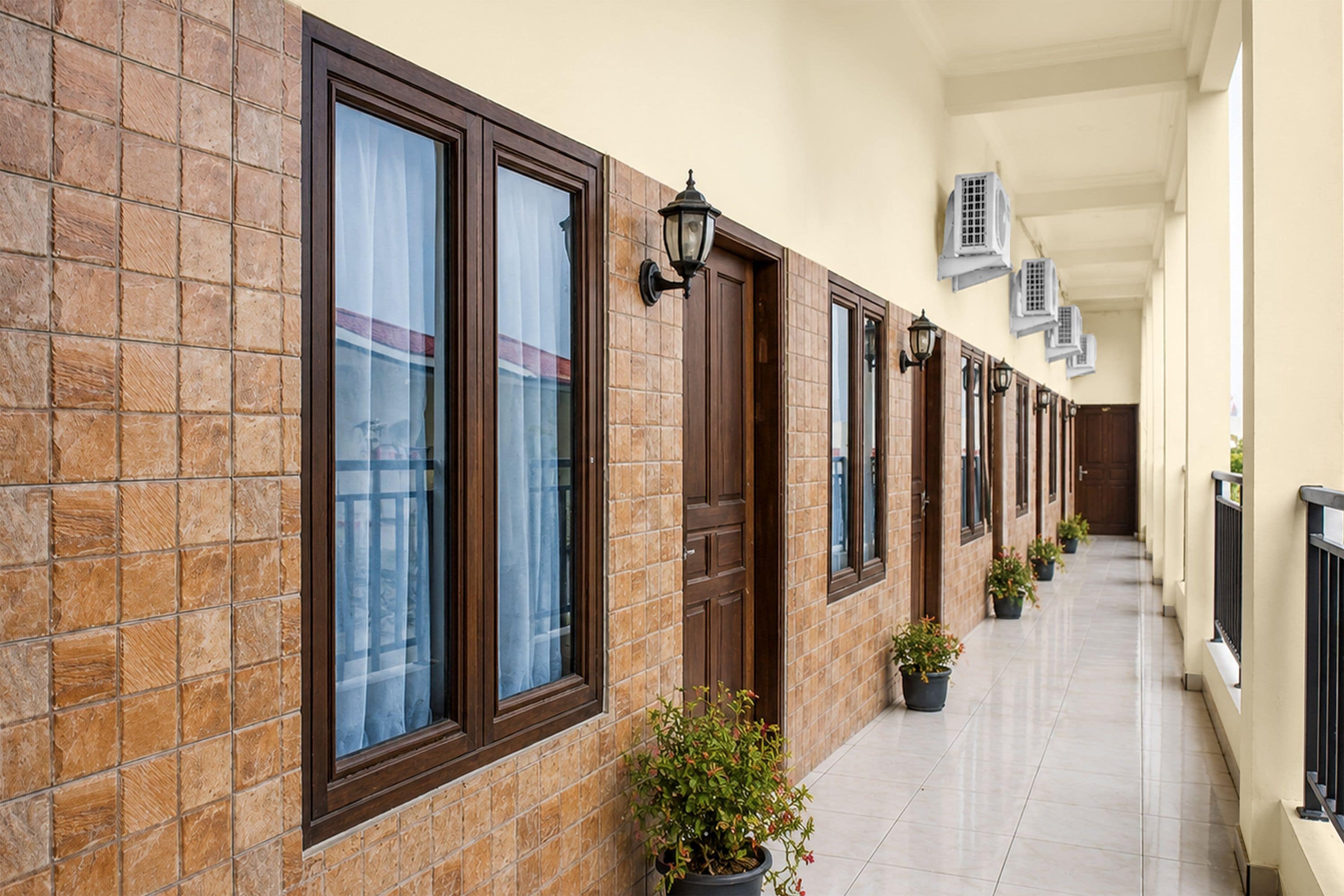 Um corredor com parede revestida de azulejos, várias janelas e aparelhos de ar condicionado.
