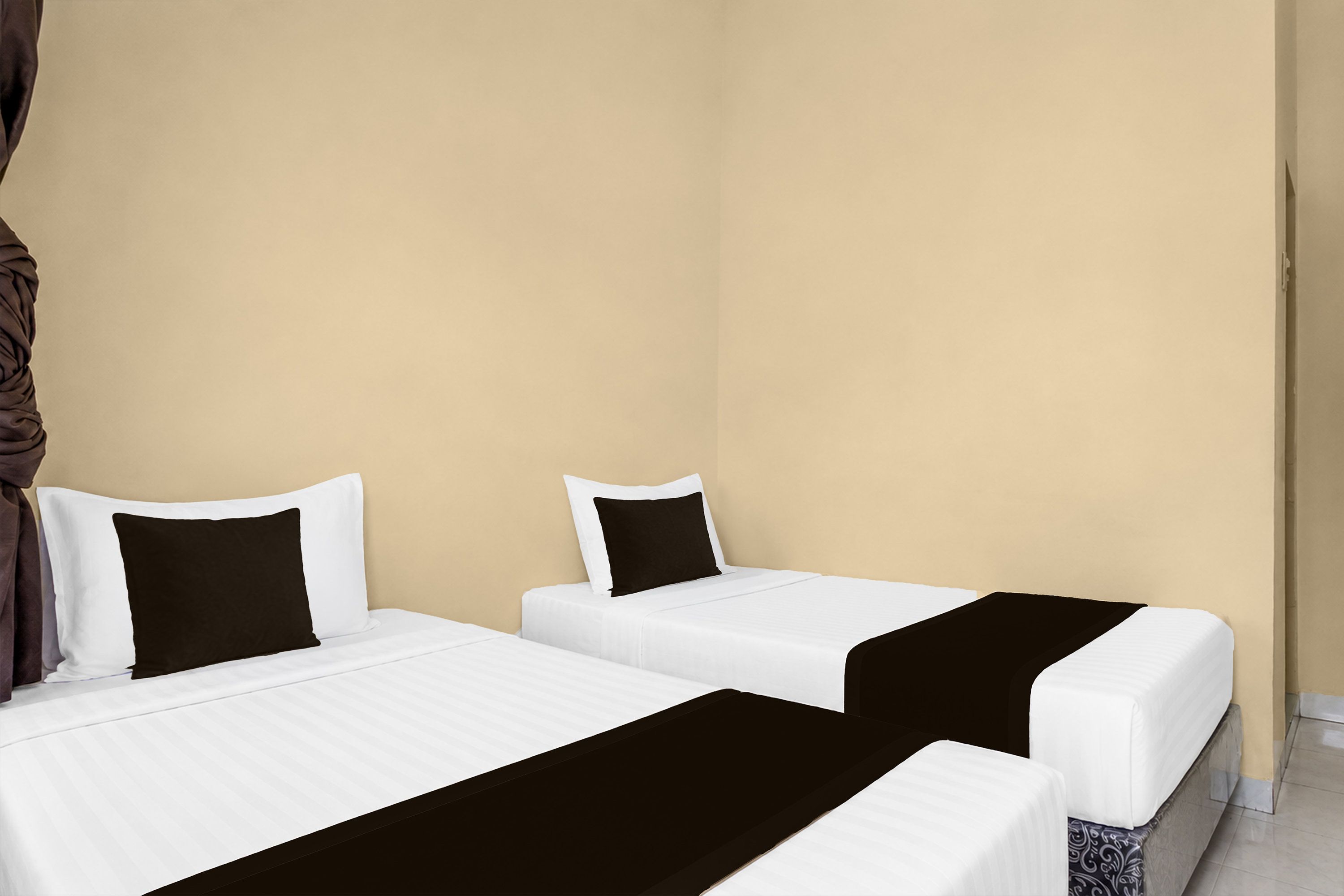 Quarto de hotel com duas camas de solteiro, cada uma com roupa de cama branca e um cobertor preto.