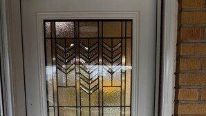 A white door with a glass panel featuring a geometric pattern.