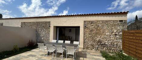 A patio with a table and chairs, a stone wall, and a wooden fence.