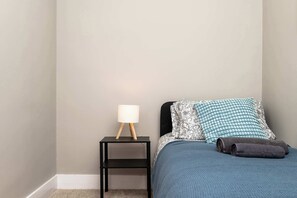 A bedroom with a bed, a nightstand with a lamp, and a wall. - Spacious Inverurie Stay -Nr Train Station -Parking (Aberdeenshire)