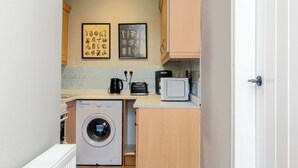 A compact kitchen with a washing machine, a toaster, and a microwave. There are two framed botanical prints on the wall. - Spacious Inverurie Stay -Nr Train Station -Parking (Aberdeenshire)