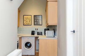 A compact kitchen with a washing machine, a toaster, and a microwave. There are two framed botanical prints on the wall. - Spacious Inverurie Stay -Nr Train Station -Parking (Aberdeenshire)