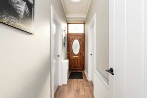 A hallway with a wooden door, white walls, and a black doormat. - Spacious Inverurie Stay -Nr Train Station -Parking (Aberdeenshire)