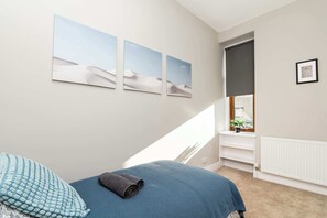 Une chambre avec un lit, une fenêtre donnant sur un beau paysage et des œuvres d’art murales.