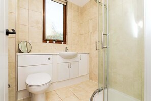 Une salle de bain avec des toilettes, un lavabo et une douche.
