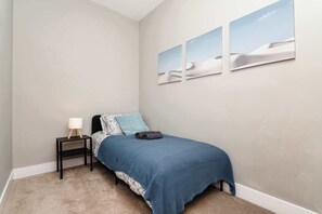 A bedroom with a bed, a nightstand, a lamp, and three wall-mounted pictures. - Spacious Inverurie Stay -Nr Train Station -Parking (Aberdeenshire)