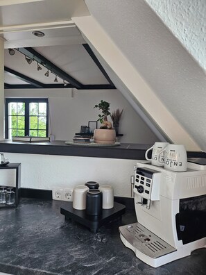 A kitchen with a coffee machine, a window with a view of greenery, and a plant on the counter. - Modern vacation rental with a balcony, near the forest (Arnsberg)