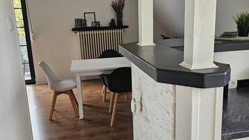 A modern kitchen with white cabinetry, a black countertop, and a dining area with a white table and chairs.