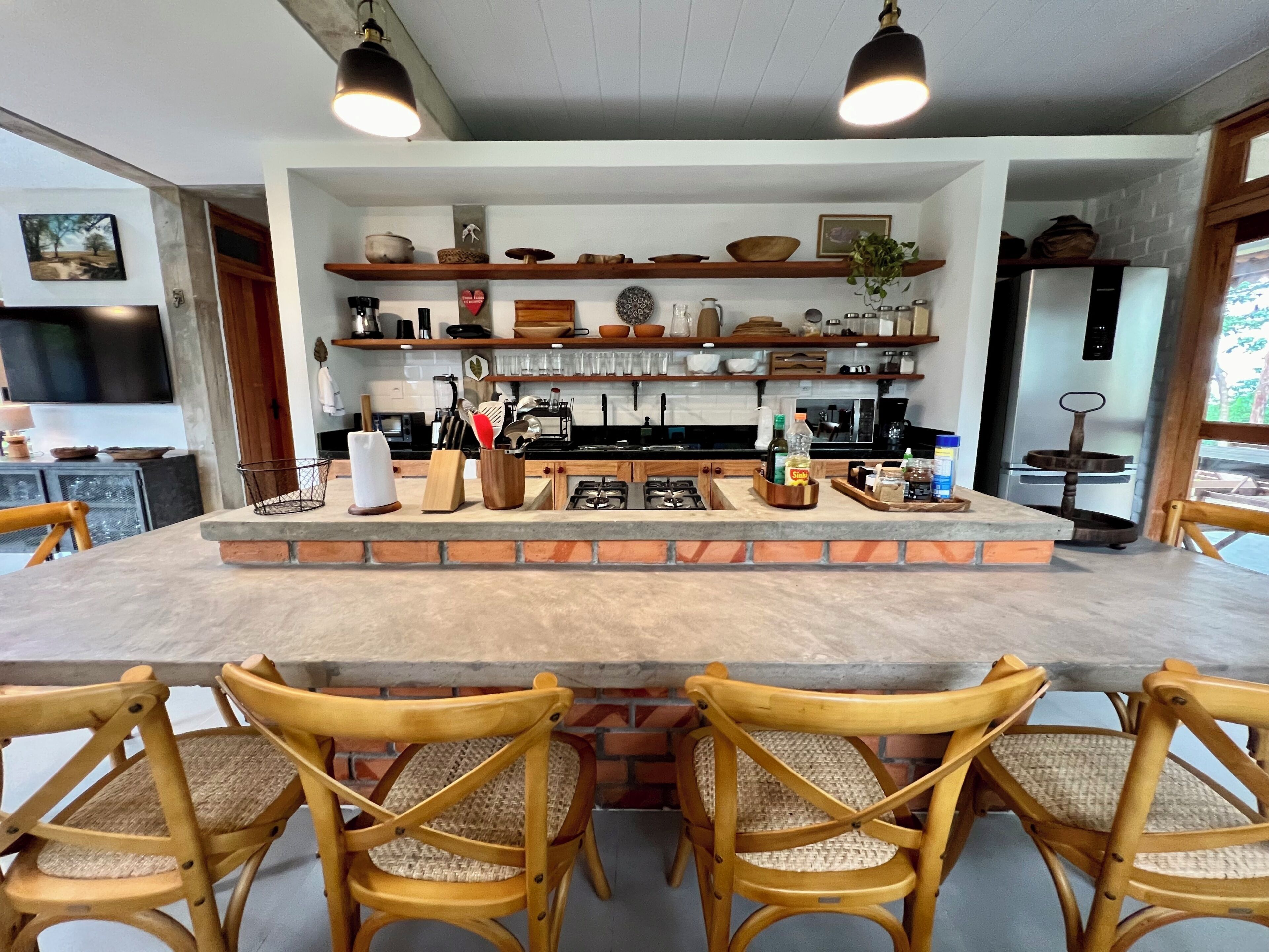 Une cuisine dotée d’un îlot central, de chaises en bois et de divers ustensiles de cuisine rangés sur des étagères.