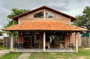 A two-story house with a tiled roof, a covered patio with outdoor seating, and a brick exterior. - Vrbo Property (Salvaterra)