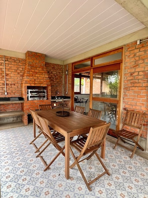 A brick fireplace, outdoor dining table, and chairs. - #2 Rosário Marajó Residence - Água Boa - Two Suites (Salvaterra)