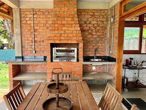 A brick-built outdoor kitchen with a built-in oven, a sink, and a wooden table with chairs. - Vrbo Property (Salvaterra)