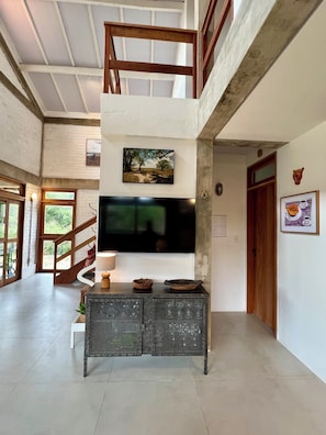 A multi-level living space with a TV, wooden staircase, and a view of greenery. - #2 Rosário Marajó Residence - Água Boa - Two Suites (Salvaterra)