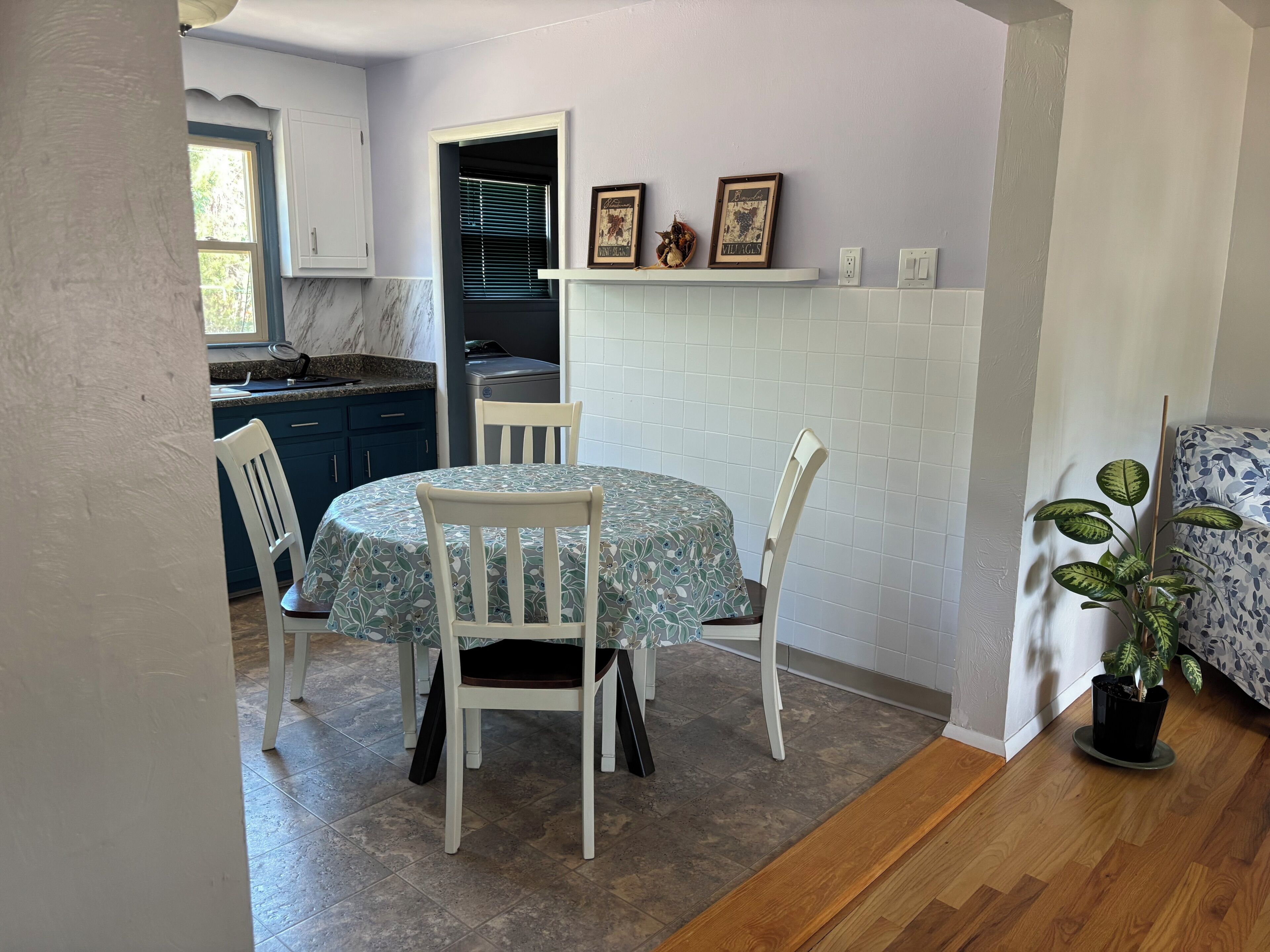 Un coin repas avec une table ronde, des chaises blanches et une plante en pot.