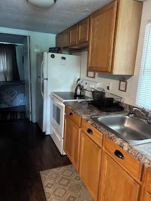 A compact kitchen with wooden cabinets, a white refrigerator, a stove, and a sink. - Lake Front Sleeps 4.  Close to Waterfalls, Parks, Golf, Fishing & Dog Friendly (Crossville)