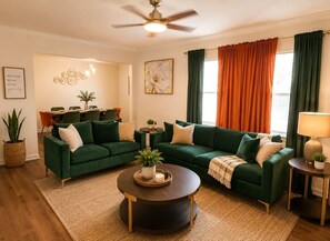 A living room with a sectional sofa, a round coffee table, and a dining area with a table and chairs. - Emerald Escape close to Airport,NRG,Medical center & ZOO With PS5 &Foosball (Houston)