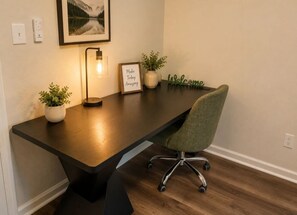 A modern office desk with a lamp, framed inspirational quote, and potted plants. - Emerald Escape close to Airport,NRG,Medical center & ZOO With PS5 &Foosball (Houston)