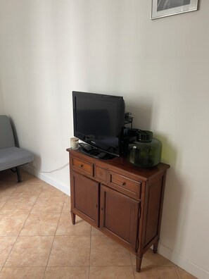 Un mueble de madera con un televisor, un control remoto y un recipiente verde encima.