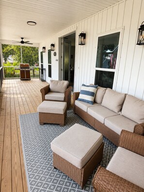 A covered porch with wicker furniture, a grill, and a patterned rug. - Paradise Beach on Perdido Bay• Dog Friendly (Pensacola)