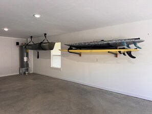Habitació amb un gran accumulador d'aigua, una finestra i una taula de surf penjada en un suport groc.