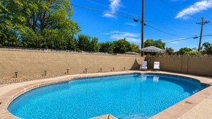 A rectangular swimming pool with a tiled edge, surrounded by a brick wall and a wooden deck. - Aloha Scottsdale, Poolside Old Town Retreat (Scottsdale)