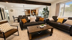 A living room with a dark brown leather sofa set, a coffee table, and a dining area in the background. - Aloha Scottsdale, Poolside Old Town Retreat (Scottsdale)