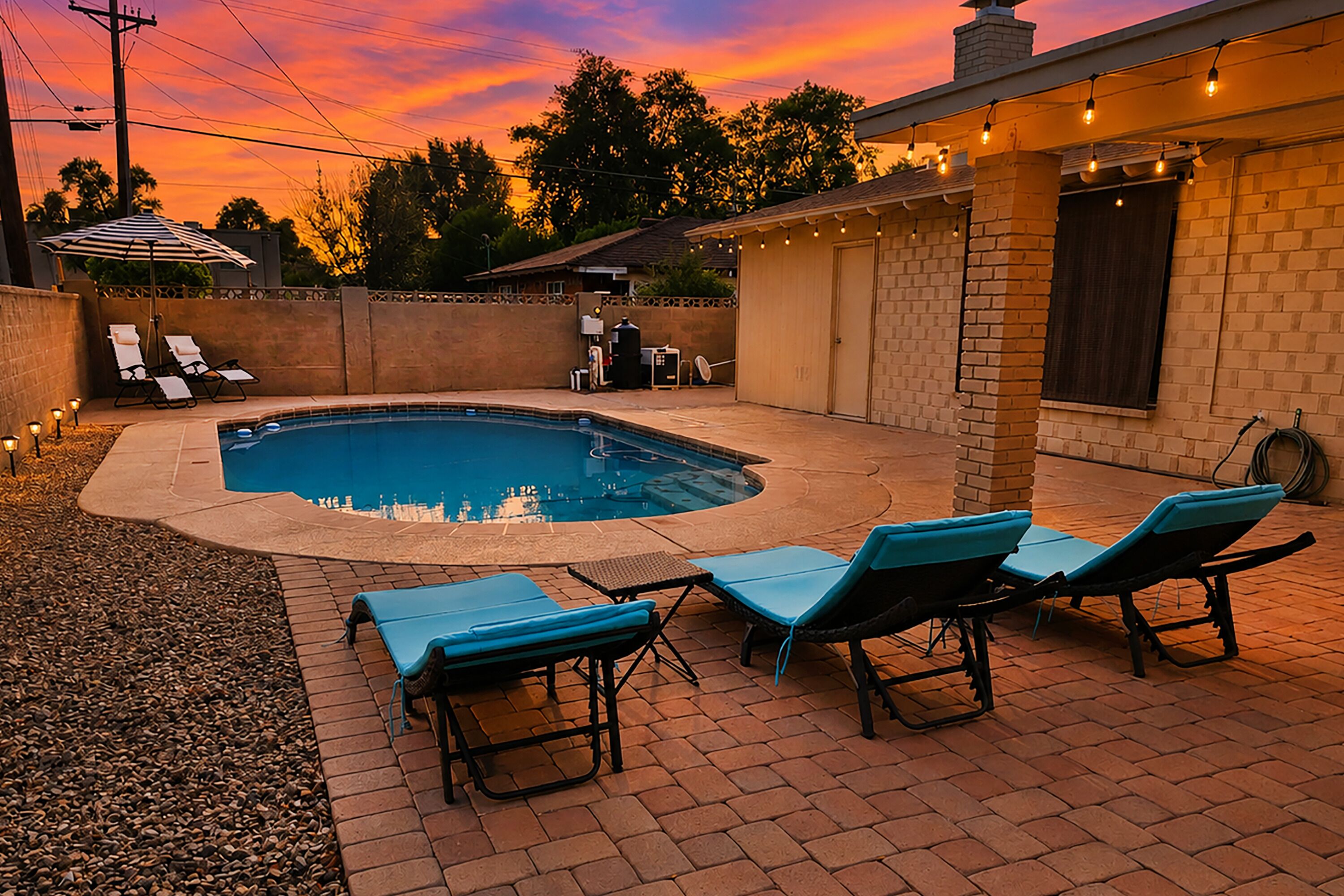 A backyard with a swimming pool, lounge chairs, and a barbecue area.