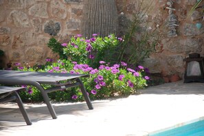 A stone wall, a metal table, and purple flowers.